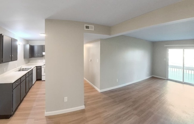 an empty living room and kitchen with wood flooring and a window