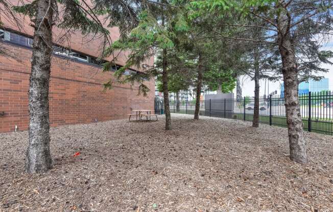 a park with trees and a bench in front of a brick building