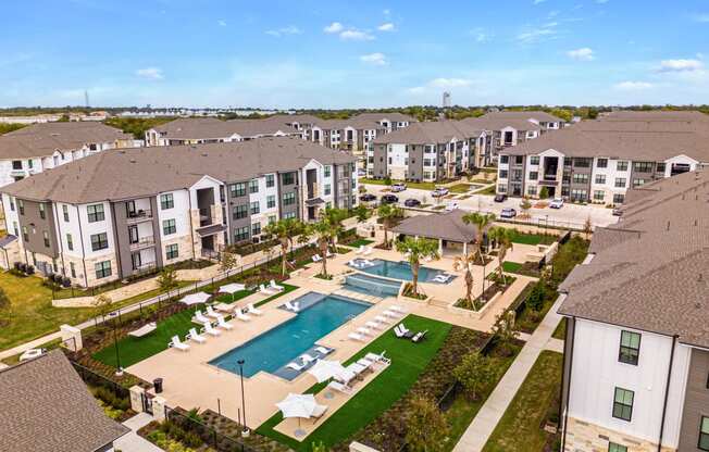 an aerial view of the resort style pool with lounge chairs and umbrellas at The Parker Austin, Pflugerville, Texas