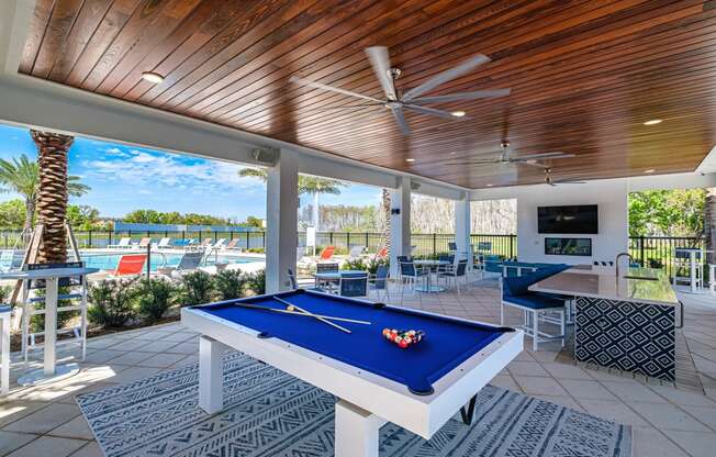 a pool table in a covered patio with a view of the pool and the beach at Altis Grand Suncoast, Land O' Lakes, 34638