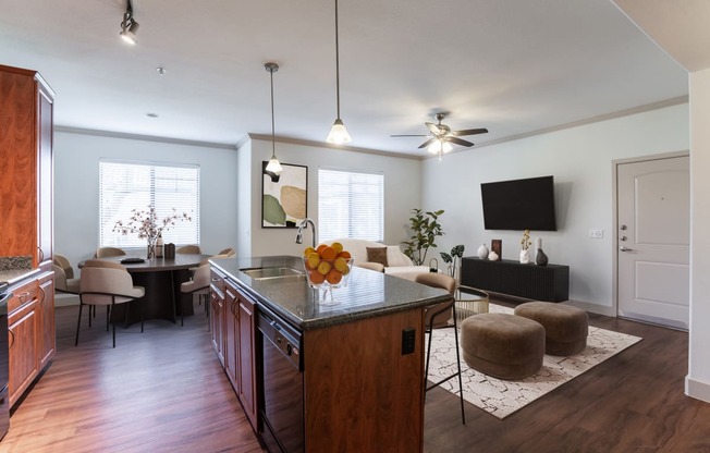 a kitchen and living room with hardwood floors and a ceiling fan