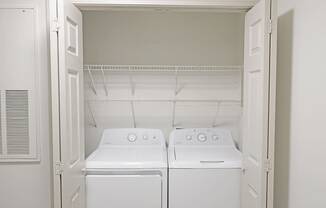 Two white front loading washing machines in a small laundry room.
