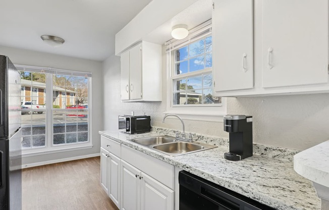 A kitchen with white cabinets and a black fridge.