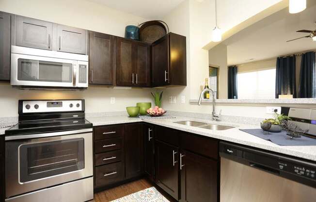 A modern kitchen with dark brown cabinets and stainless steel appliances.