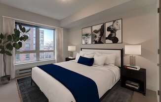 A bedroom with a large bed and a window overlooking a city.