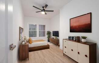 A bedroom with a bed, dresser, and a ceiling fan at Westmore Manor Apartments, Los Angeles