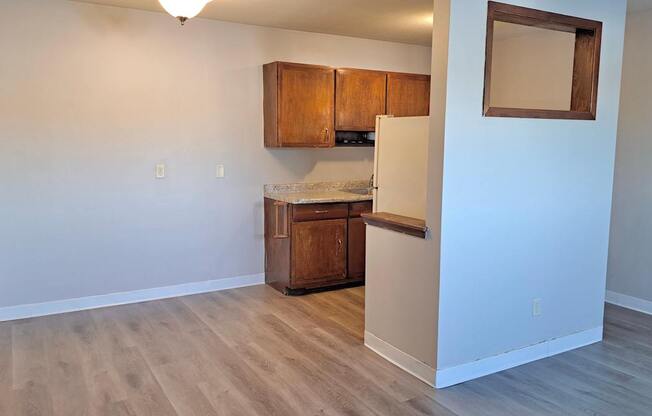 A kitchen area with wooden cabinets and a fridge.