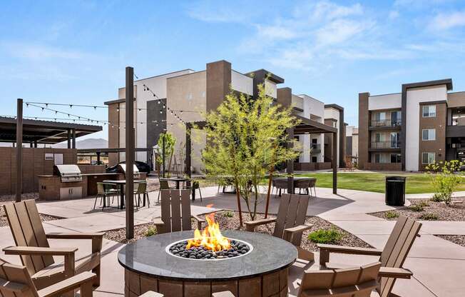 A fire pit sits in the middle of a patio surrounded by chairs.
