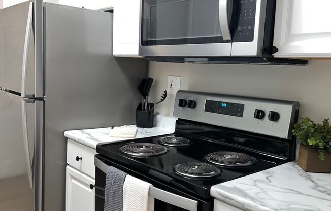 a small kitchen with a stove and microwave and a refrigerator