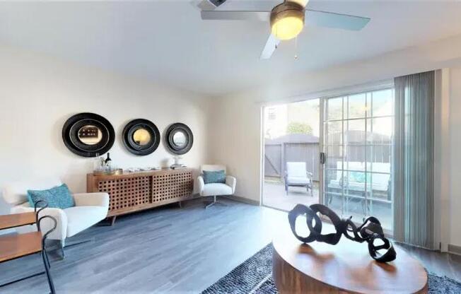 A living room with a white sofa, a wooden coffee table, and a ceiling fan.