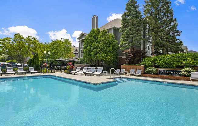 a swimming pool with chairs and a building in the background
