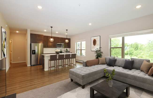 Eagan, MN Glen Pond Addition Apartment. A living room with a couch, coffee table, and large window with a kitchen in the background.