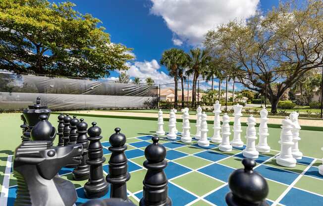 A giant chess set is set up on a green and blue checkered field.