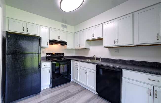 a kitchen with white cabinets and black appliances