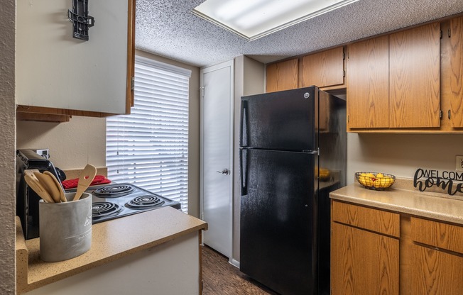 A black refrigerator sits in a kitchen next to a counter.