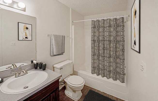 A bathroom with a toilet, sink, and shower curtain.