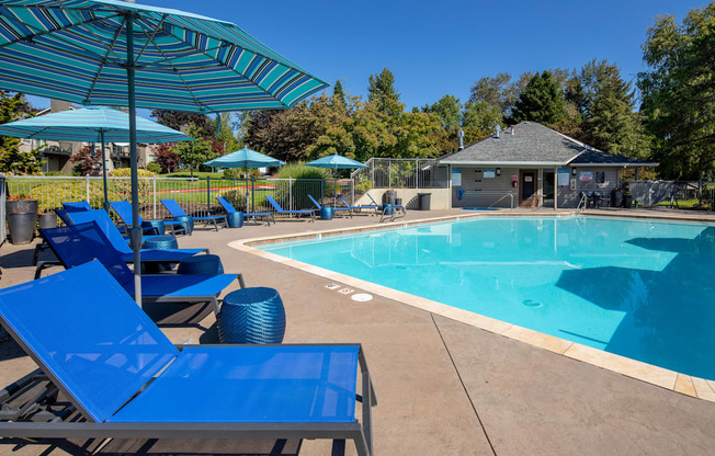 our resort style swimming pool with blue chairs and umbrellas