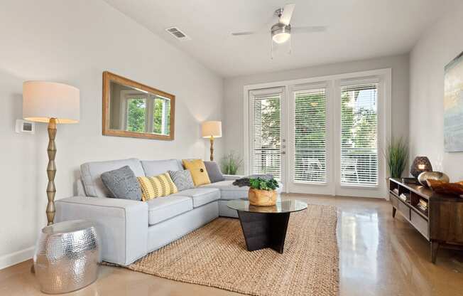a living room with white walls and a white couch with yellow and gray pillows