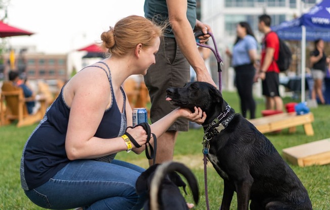 a woman petting a black dog on a leash at Allied Harbor Point, Maryland