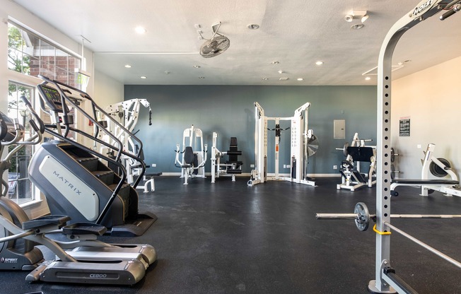 a gym with cardio equipment and weights on the floor