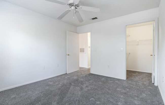 A room with a ceiling fan and carpeted floor.
