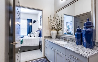 a bathroom with a sink and a mirror and a door to a bedroom