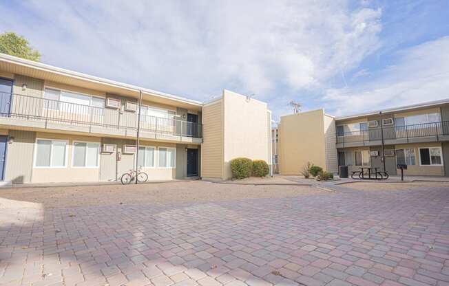 the outlook of two apartment buildings with a brick courtyard