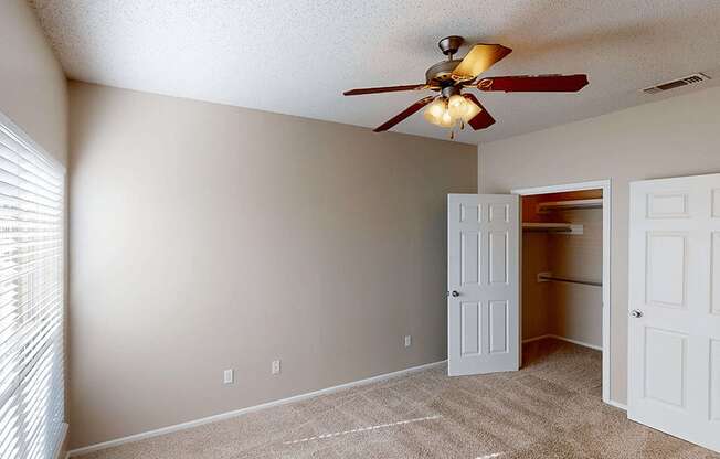 a bedroom with a ceiling fan and closet