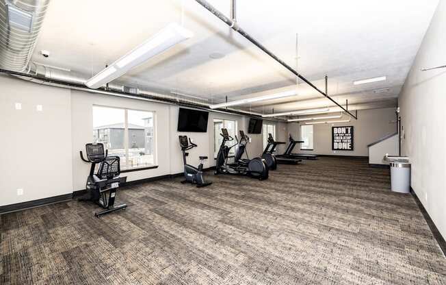 A gym with a variety of equipment including treadmills, weights, and exercise bikes.