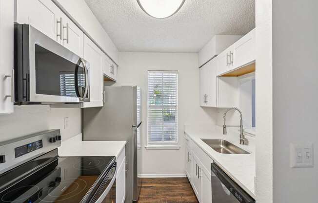 A kitchen with white cabinets and a black microwave.