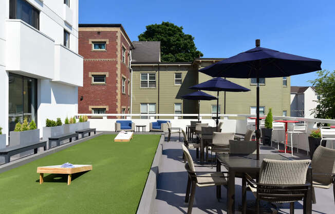 A patio with a table and chairs and umbrellas.