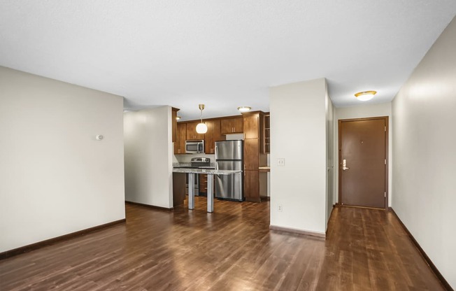 an empty living room and kitchen with a wood floor and white walls