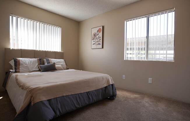 A bedroom with a bed, pillows, and a framed picture on the wall.