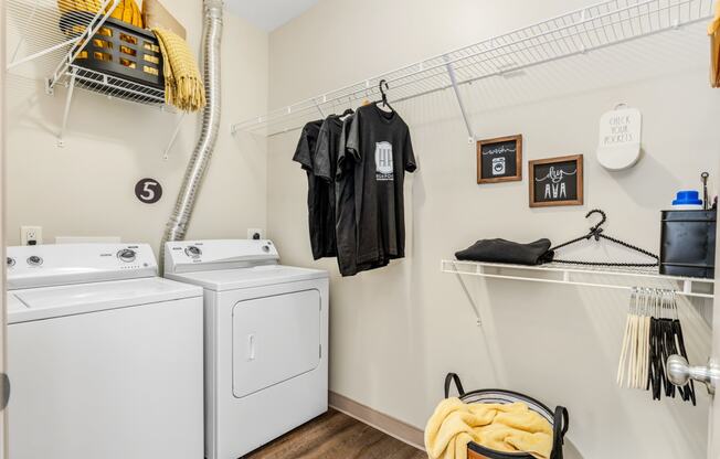 a washer and dryer in a laundry room with clothes hanging on the wall