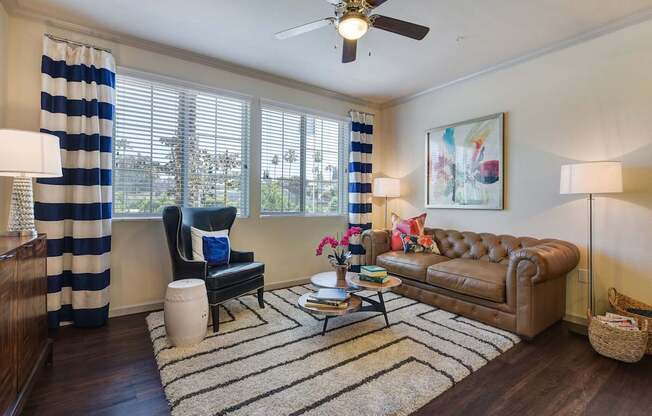 A living room with a brown leather couch, a black chair, and a striped curtain.
