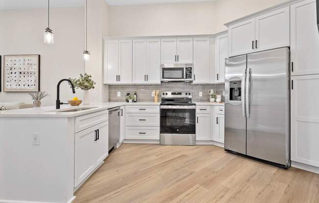 A modern kitchen with white cabinets and stainless steel appliances.