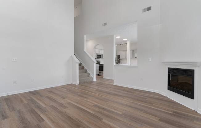 a living room with white walls and a fireplace and wooden floors