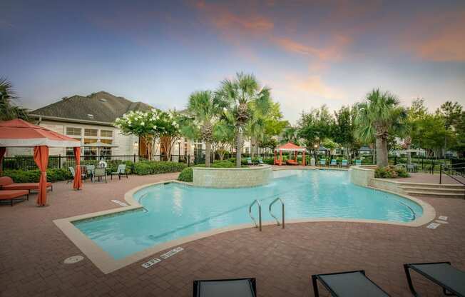 a resort style pool with lounge chairs and umbrellas