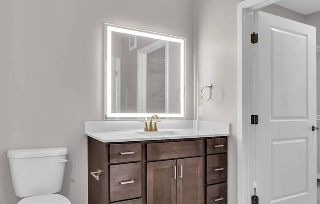 A bathroom with a white toilet, a sink with a mirror above it, and a white door.