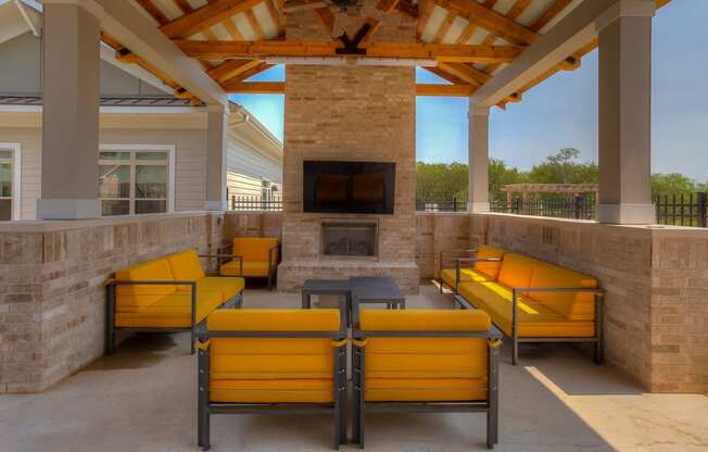 a covered patio with a fireplace and yellow couches