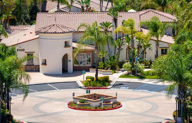 A white house with a red roof and a garden in front.