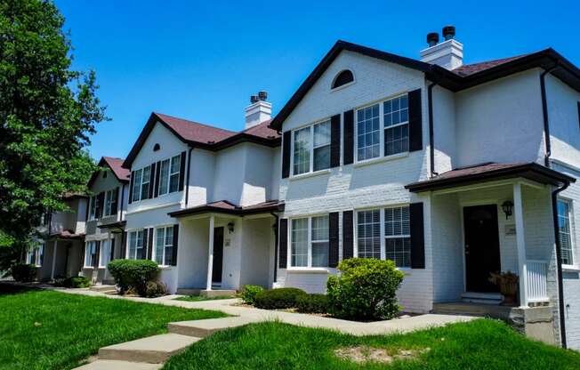 a row of white houses with green grass and a blue sky