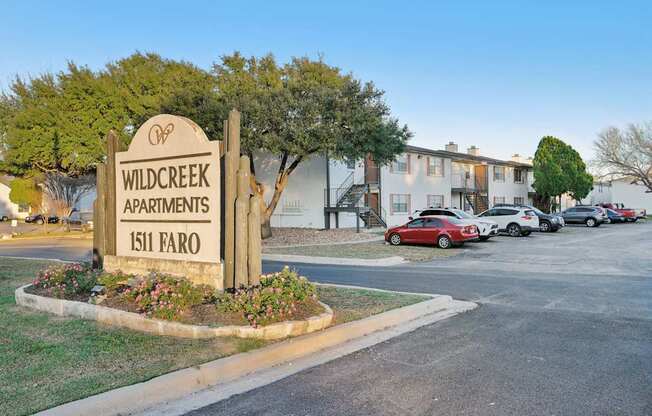 A sign for Wildcreek Apartments stands in front of a building.
