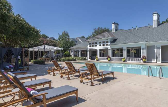a swimming pool with chaise lounge chairs and a building in the background at Seasons at Umstead apartments in Raleigh