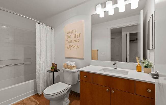 A bathroom with a toilet, sink, and mirror.