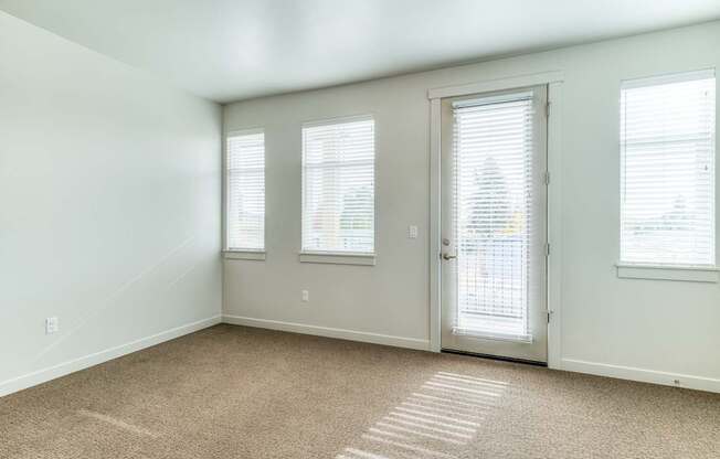 A room with a carpeted floor and a door with a window on the side.