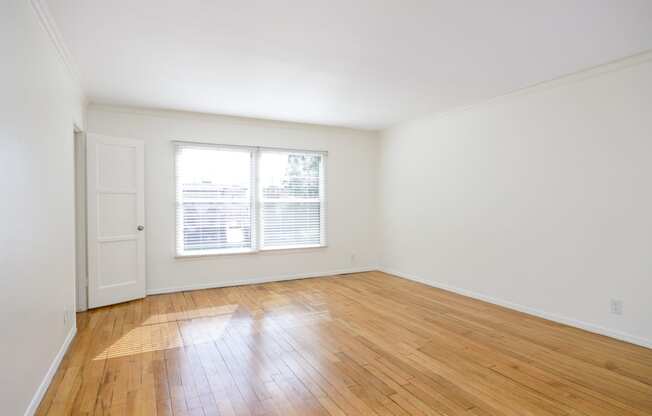 an empty living room with wood floors and a window