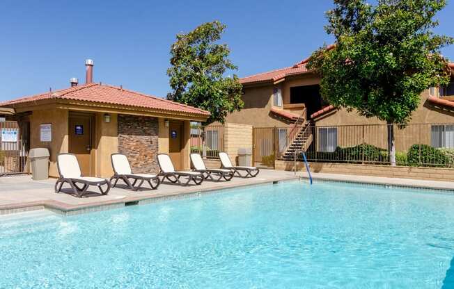 a swimming pool with chairs in front of a house