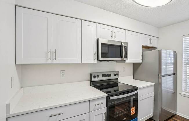 A kitchen with white cabinets and appliances.