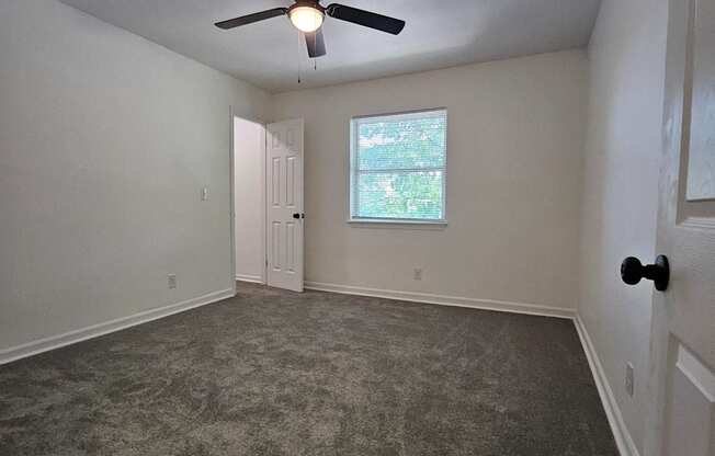 an empty living room with a ceiling fan and a window